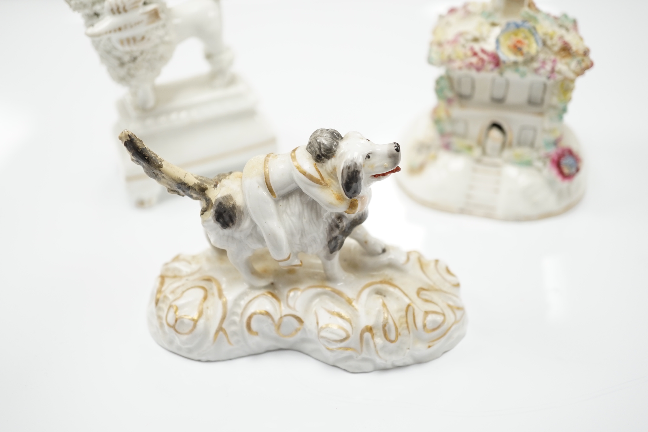 Three Staffordshire porcelain dog figures, c.1830-50, comprising a boy clinging to the back of a spaniel, a model of a poodle with a bird in its mouth and a model of a cottage with a small dog in the doorway, tallest 9cm